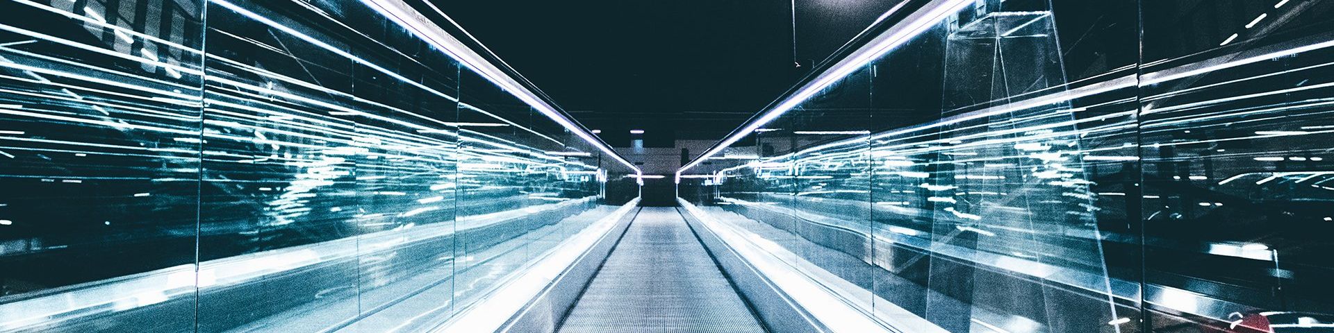 Grey conveyor between glass frames at night